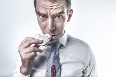 man looking worries eating a pastry