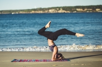 woman doing a headstand on the beach