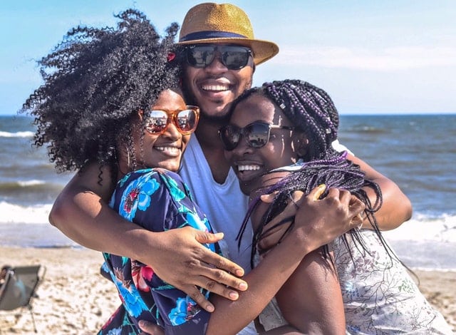 three friends hugging on the beach