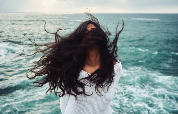 woman's hair blowing in wind by ocean
