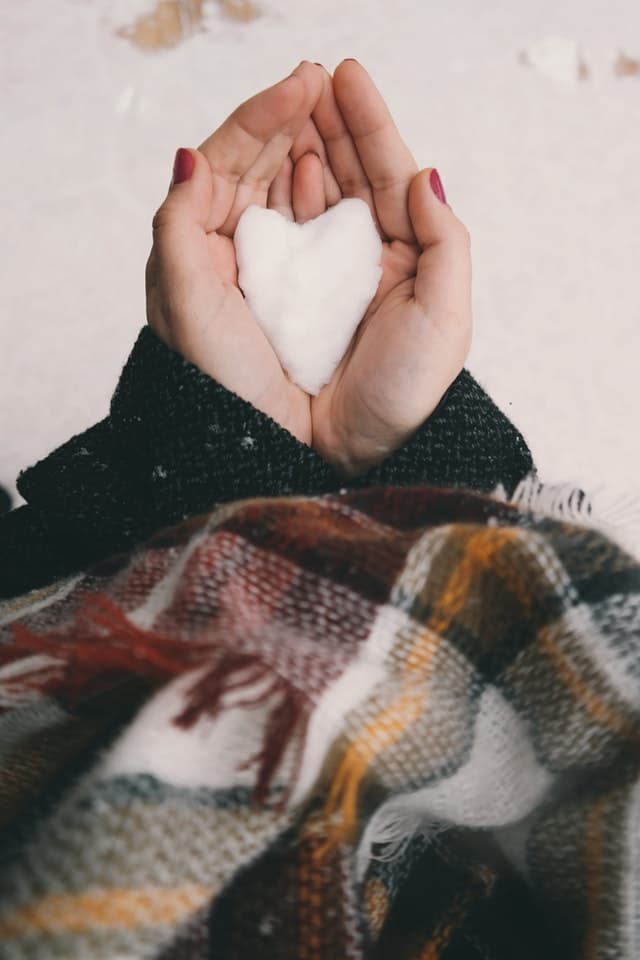 woman holding snow heart in hands