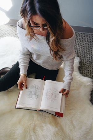 woman reads chinese medicine textbook on sheepskin rug