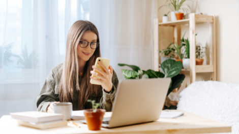 woman looking at phone and computer in home office while being exposed to blue light