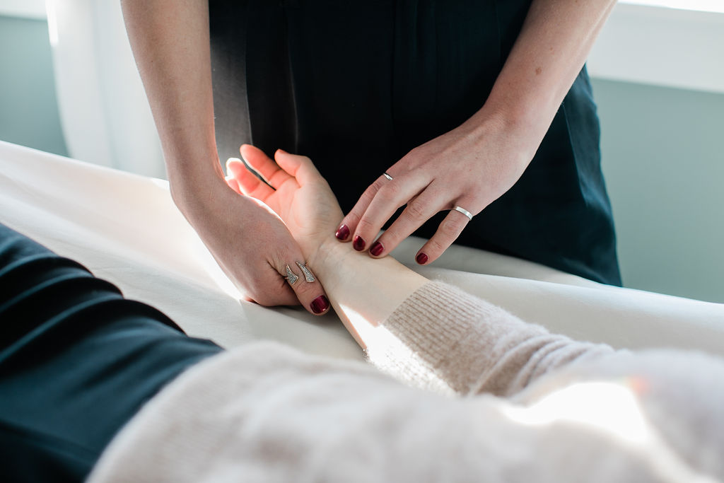 woman checking a patient's heart rate before getting acupuncture treatment